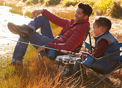 Dad and son sitting near water and fishing